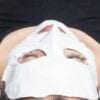 A woman wearing a brightening mask after a dermaplaning treatment.