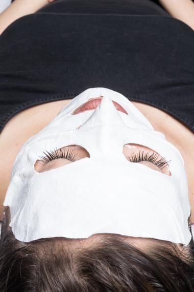 A woman wearing a brightening mask after a dermaplaning treatment.