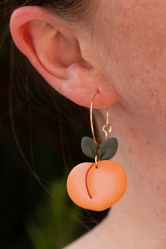 Handmade, peach-shaped, clay dangle earrings by Speckled Designs.